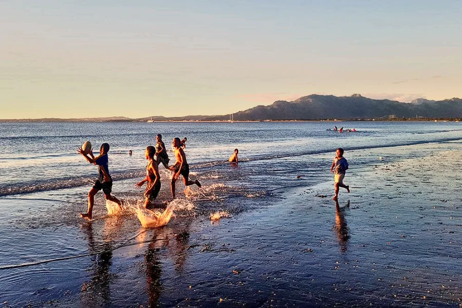 Children playing in the shallows at Wailoaloa Beach at dusk